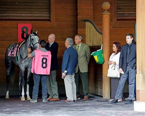 Trainer Chris Block adjusts his horse's reins while his family looks after him.