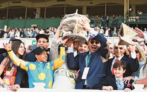 American Pharoah&#39;s owner Ahmed Zayat holds the Belmont Stakes Trophy aloft, center with the help of jockey Victor Espinoza, left as trainer Bob Baffert raises the Triple Crown trophy aloft after his trainee made his way to the record books by winning the 147th running of the Belmont Stakes and thoroughbred racing&#39;s Triple Crown June 6, 2015 at Belmont Park in Elmont, N.Y.   