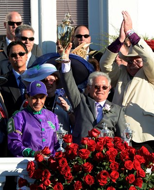 Victor Espinoza, left stands with trainer Art Sherman as he holds the winner's trophy aloft after winning the 140th running of The Kentucky Derby with California Chrome Saturday evening May 3, 2014 in Louisville, Kentucky
