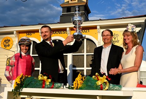 Coach Mike McCarthy raises the winner's trophy after Rombauer with driver Flavien Prat won the 146th run of the Preakness Stakes at Pimlico Raceway Saturday, May 15, 2021 in Baltimore, MD. 