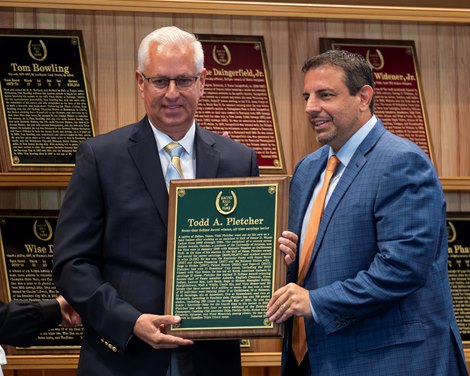 Owner Mike Repole, right assists  inductee trainer Todd Pletcher with the plaque of honor during the Hall of Fame Inductions at the Fasig Tipton sales pavilion Friday Aug 6, 2021 in Saratoga Springs, N.Y. Photo  by Skip Dickstein