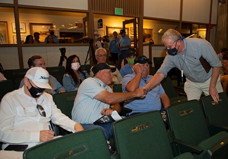 (L-R): Don Adams, signing ticket, as Ernie Retamoza is congratulated by Pat Costello, right, with Paramount as Mike Cliine is on phone. Hip 89 filly by Uncle Mo out of Nikki’s Choice at Paramount<br><br />
Keeneland September yearling sales on Sept. 13, 2021. 