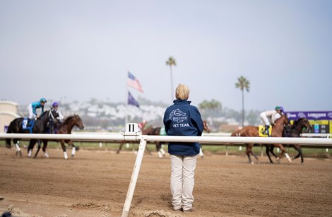 A vet looks on as horses canter to post<br>
Del Mar 5.11.21