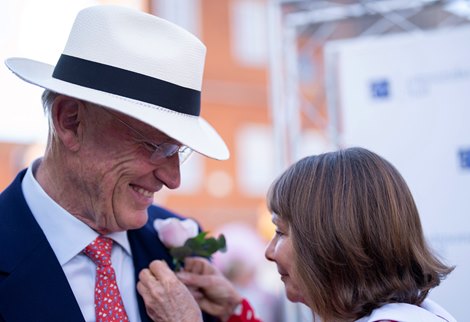 Lady Jane Cecil attaches a pink rose to John Gosden's lapel after the Sir Henry Cecil Stakes<br>
Newmarket 7.7.22 Pic: Edward Whitaker
