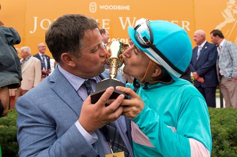 Jockey Rafael Hernandez and trainer Kevin Attard kiss the Queen&#39;s Plate trophy after Moira captures the 163rd running of the Queens&#39; Plate Stakes at Woodbine
