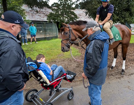 Cody Dorman meets his namesake Cody's Wish who his held by trainer Billy Mott in the barn are on the grounds of the Oklahoma Training enter adjacent to the Saratoga Race Course Friday, Aug. 4, 2023 in Saratoga Springs, N.Y. Dorman was born with a rare genetic disorder called Wolf-Hirschhorn syndrome, leaving him unable to walk and communicate without using a tablet. In 2018, he and his family participated in a Make-A-Wish at a Kentucky farm, where a foal came up to Dorman. After Cody's Wish laid his head on Dorman's lap, a bond was born. Photo by Skip Dickstein Cody Dorman meets his namesake Cody's Wish who his held by trainer Billy Mott in the barn are on the grounds of the Oklahoma Training enter adjacent to the Saratoga Race Course Friday, Aug. 4, 2023 in Saratoga Springs, N.Y. Dorman was born with a rare genetic disorder called Wolf-Hirschhorn syndrome, leaving him unable to walk and communicate without using a tablet. In 2018, he and his family participated in a Make-A-Wish at a Kentucky farm, where a foal came up to Dorman. After Cody's Wish laid his head on Dorman's lap, a bond was born. Photo by Skip Dickstein