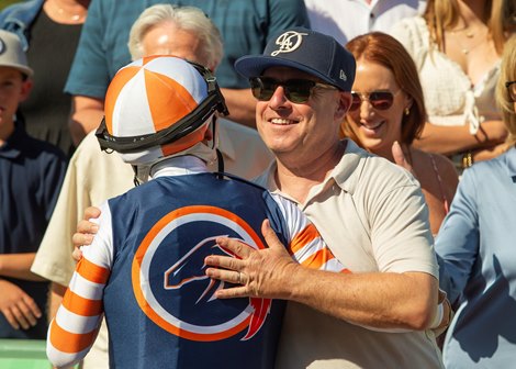 Gary Fenton of Little Red Feather Racing, right, has a hug for jockey Hector Berrios, left, in the winner's circle after their victory in the Grade III, $100,000 Surfer Girl Stakes, Sunday, October 6, 2024 at Santa Anita Park, Arcadia CA. © BENOIT PHOTO